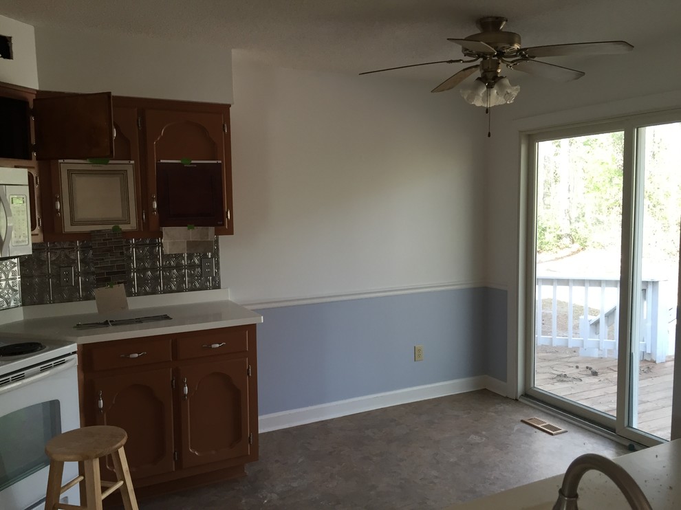 Home design - mid-sized transitional galley vinyl floor home design idea with a farmhouse sink, raised-panel cabinets, beige cabinets, solid surface countertops, multicolored backsplash, stone tile backsplash, stainless steel appliances and no island