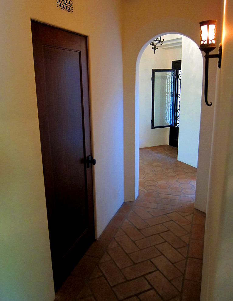 This is an example of a mid-sized mediterranean hallway in Santa Barbara with white walls, terra-cotta floors and red floor.