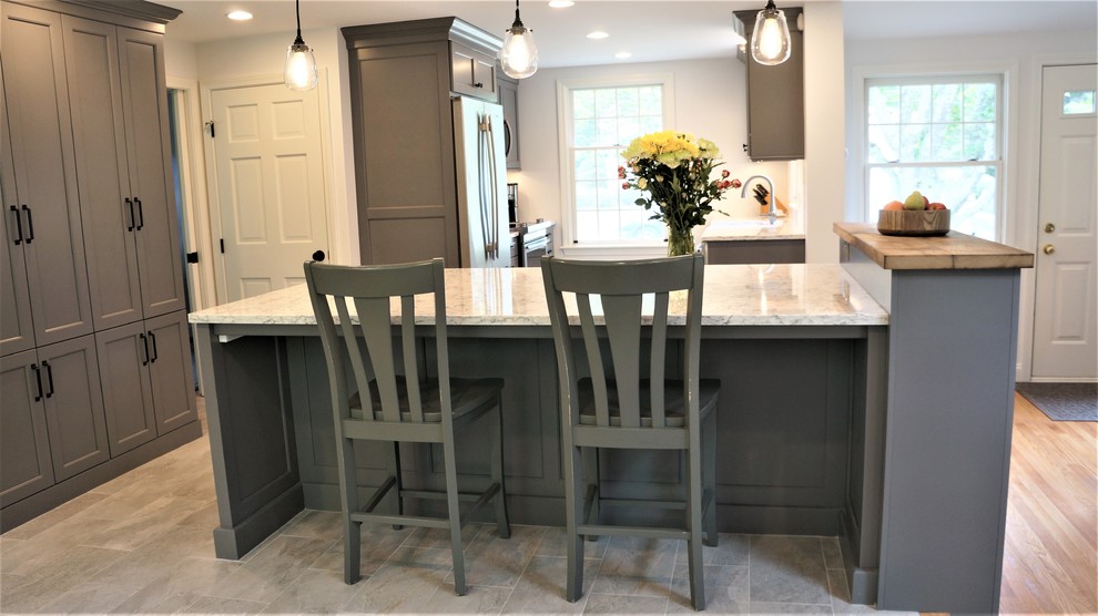 Open concept kitchen - mid-sized transitional galley porcelain tile and gray floor open concept kitchen idea in Boston with a farmhouse sink, recessed-panel cabinets, quartz countertops, white backsplash, porcelain backsplash, stainless steel appliances, an island and white countertops