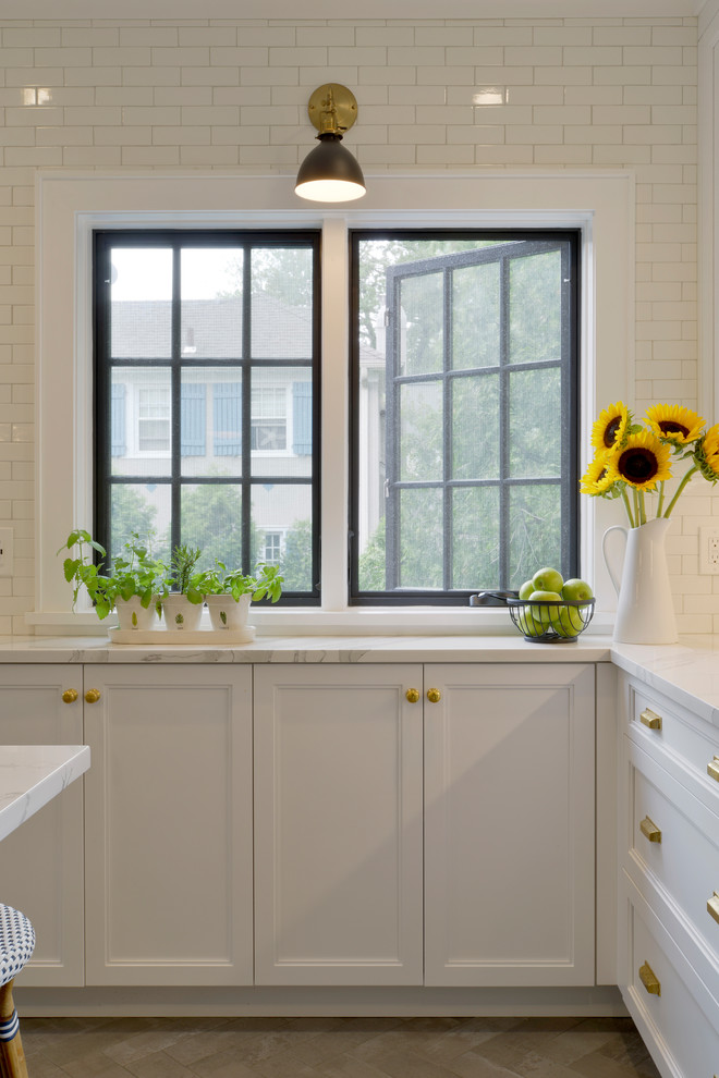 Example of a small transitional u-shaped porcelain tile and gray floor enclosed kitchen design in New York with an undermount sink, recessed-panel cabinets, white cabinets, quartz countertops, white backsplash, ceramic backsplash, stainless steel appliances, an island and white countertops