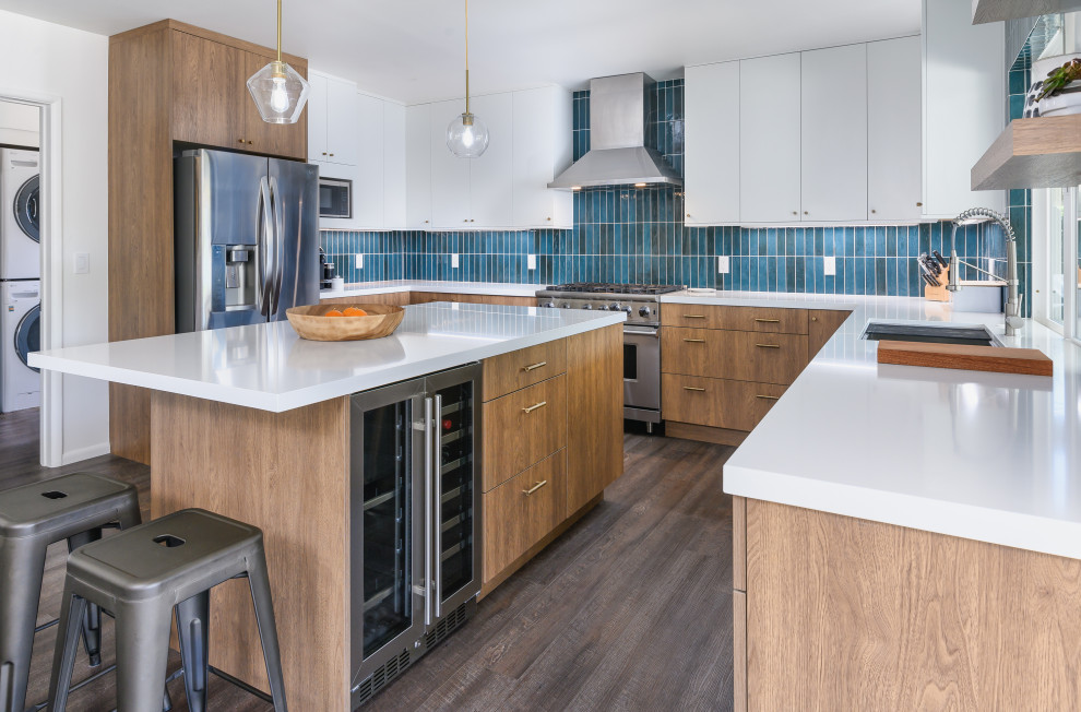 Bild på ett stort funkis vit vitt kök, med en enkel diskho, släta luckor, bruna skåp, bänkskiva i kvarts, blått stänkskydd, stänkskydd i keramik, rostfria vitvaror, vinylgolv, en köksö och brunt golv