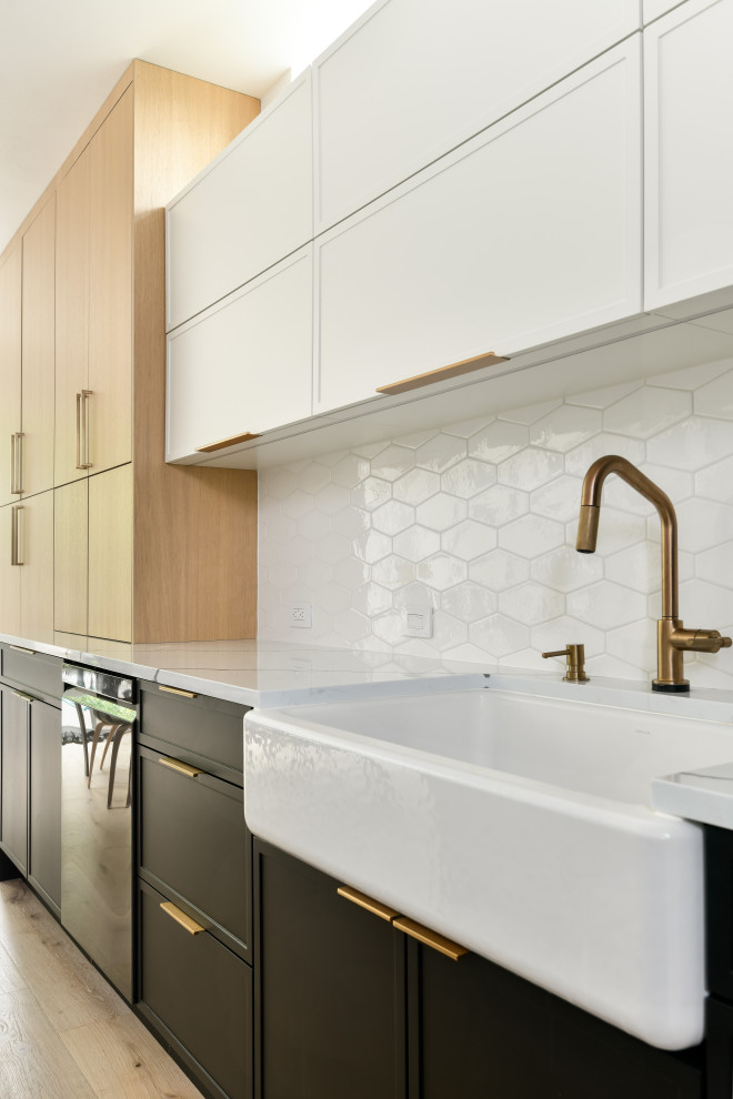 Example of a large minimalist single-wall medium tone wood floor and yellow floor eat-in kitchen design in Seattle with a farmhouse sink, shaker cabinets, black cabinets, quartz countertops, white backsplash, porcelain backsplash, stainless steel appliances, an island and white countertops