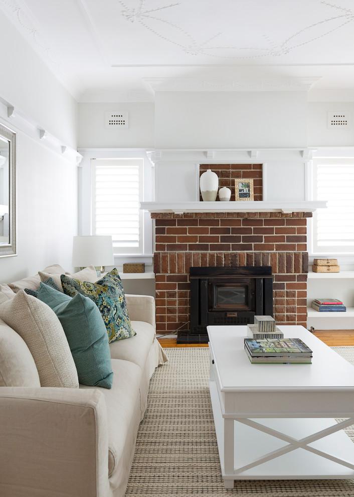 Inspiration for a small country open concept living room in Sydney with white walls, medium hardwood floors, a standard fireplace, a brick fireplace surround and brown floor.