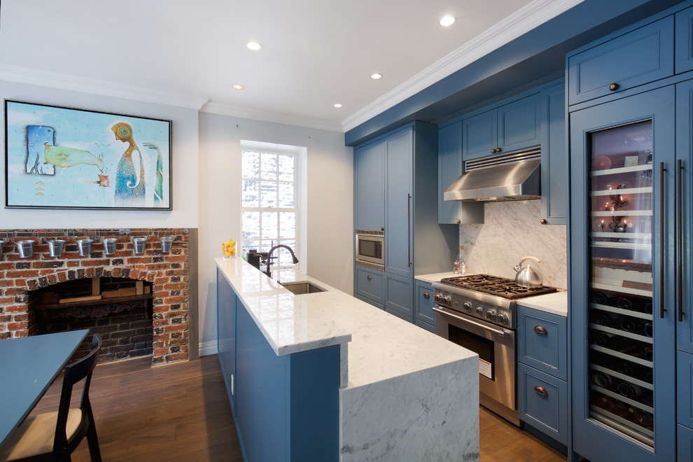 Inspiration for a mid-sized eclectic kitchen in New York with an undermount sink, recessed-panel cabinets, blue cabinets, marble benchtops, grey splashback, marble splashback, stainless steel appliances, medium hardwood floors, a peninsula and brown floor.