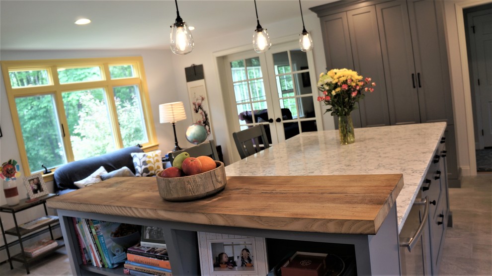 Example of a mid-sized transitional galley porcelain tile and gray floor open concept kitchen design in Boston with a farmhouse sink, recessed-panel cabinets, quartz countertops, white backsplash, porcelain backsplash, stainless steel appliances, an island and white countertops