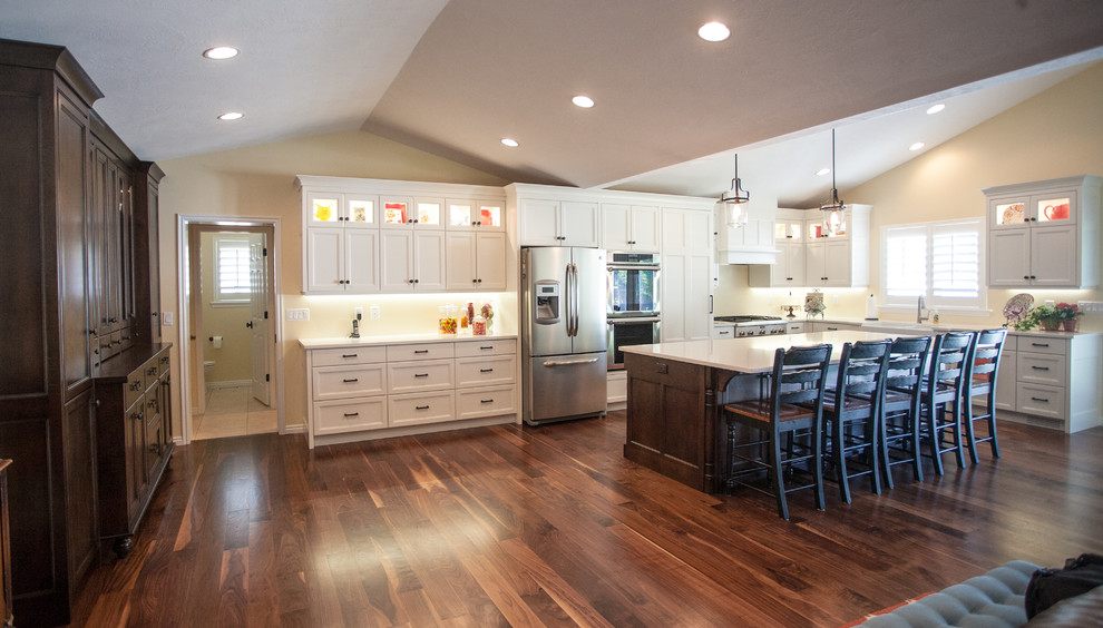 Photo of a large traditional l-shaped kitchen pantry in Salt Lake City with a farmhouse sink, shaker cabinets, white cabinets, quartz benchtops, stainless steel appliances, dark hardwood floors and with island.