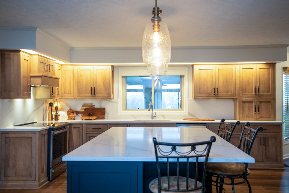 Inspiration for a large transitional l-shaped medium tone wood floor and brown floor eat-in kitchen remodel with a single-bowl sink, shaker cabinets, medium tone wood cabinets, quartz countertops, white backsplash, quartz backsplash, stainless steel appliances, an island and white countertops
