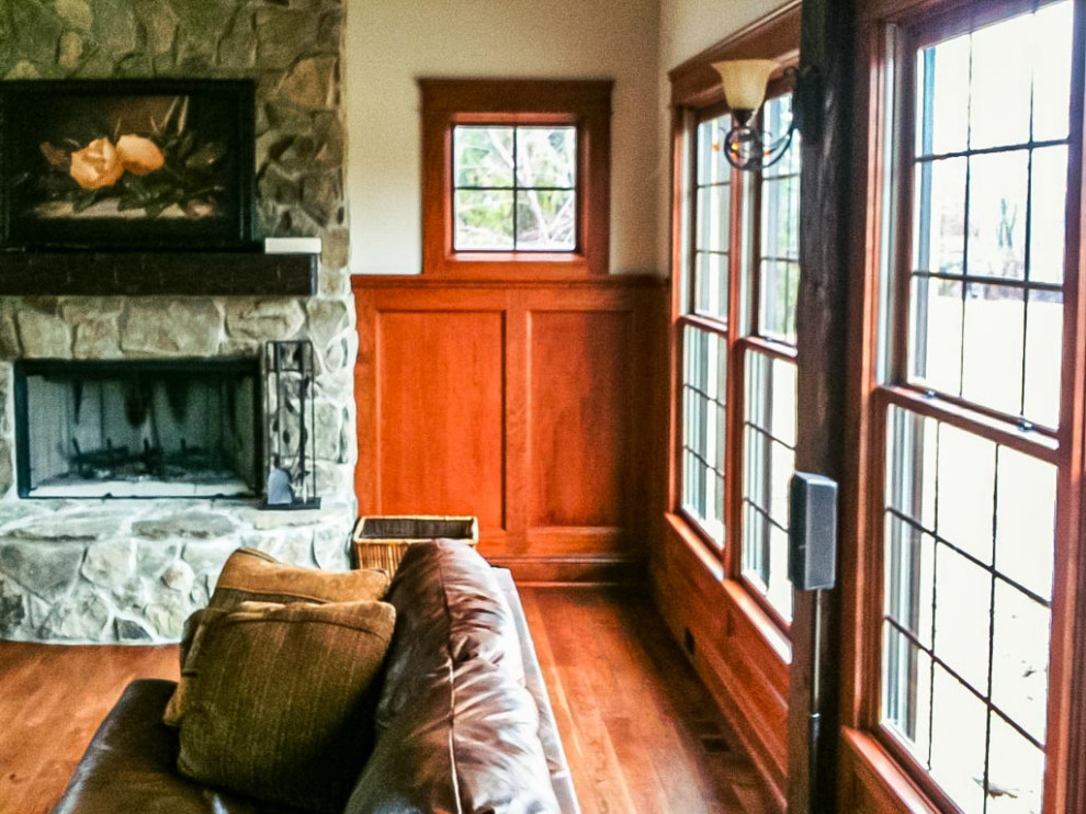 This is an example of a formal open concept living room in Cleveland with beige walls, dark hardwood floors, a standard fireplace, a stone fireplace surround, brown floor, exposed beam and decorative wall panelling.