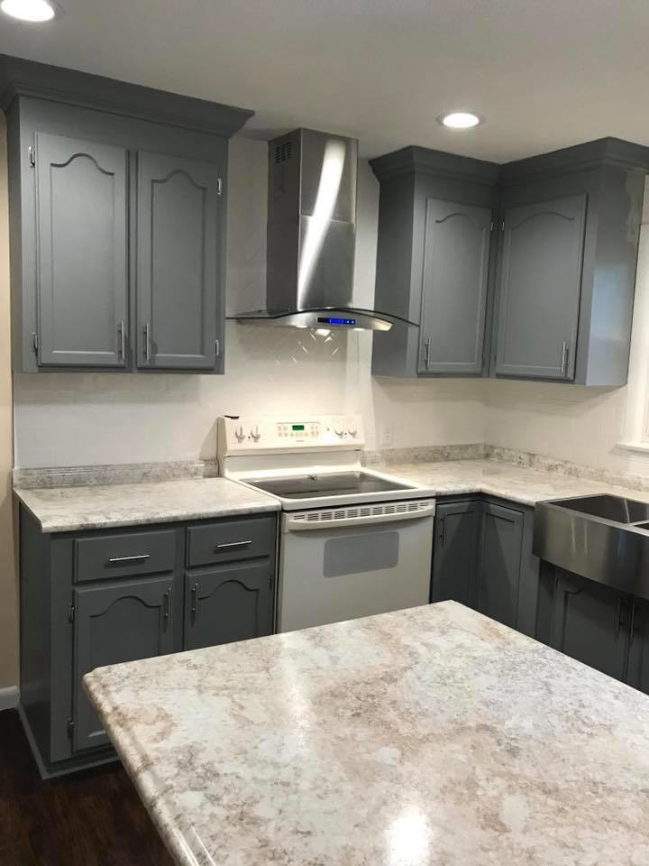 Eat-in kitchen - mid-sized transitional l-shaped medium tone wood floor and brown floor eat-in kitchen idea with a farmhouse sink, shaker cabinets, white cabinets, marble countertops, gray backsplash, stainless steel appliances, an island and gray countertops