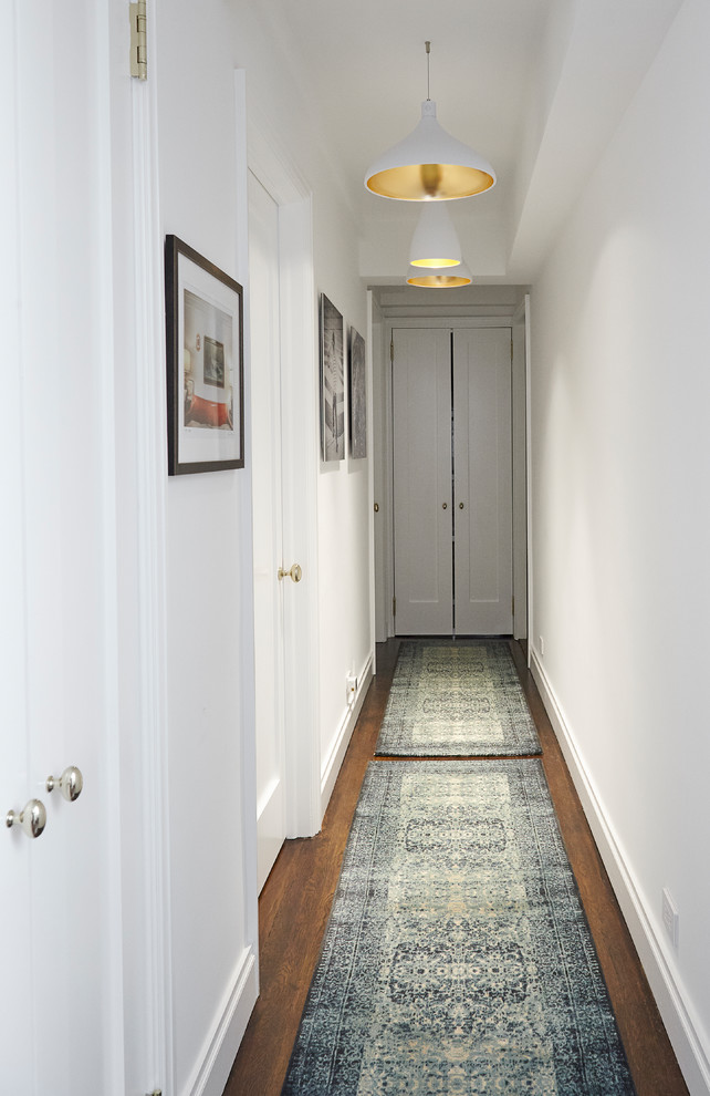 Inspiration for a small transitional hallway in New York with white walls, dark hardwood floors and brown floor.