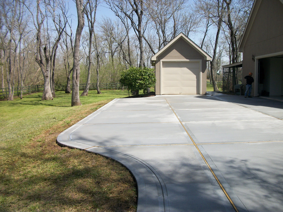 This is an example of a large traditional backyard driveway in Houston with concrete pavers.
