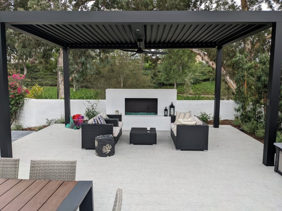 This is an example of a contemporary back patio in Orange County with a fireplace, tiled flooring and a pergola.