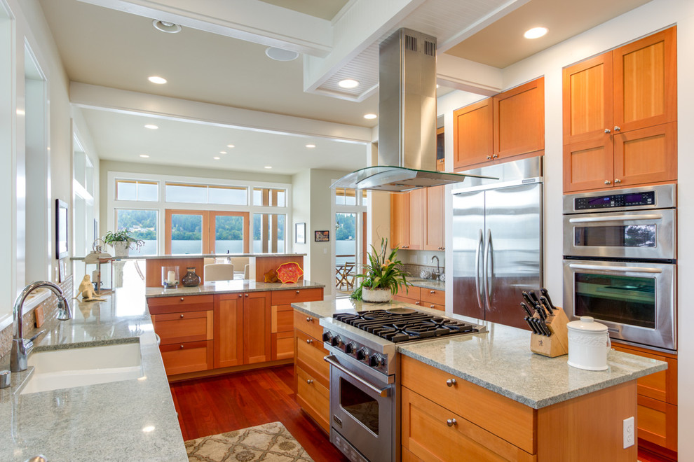 Photo of a large beach style u-shaped separate kitchen in Seattle with an undermount sink, shaker cabinets, medium wood cabinets, granite benchtops, beige splashback, stainless steel appliances, medium hardwood floors and with island.