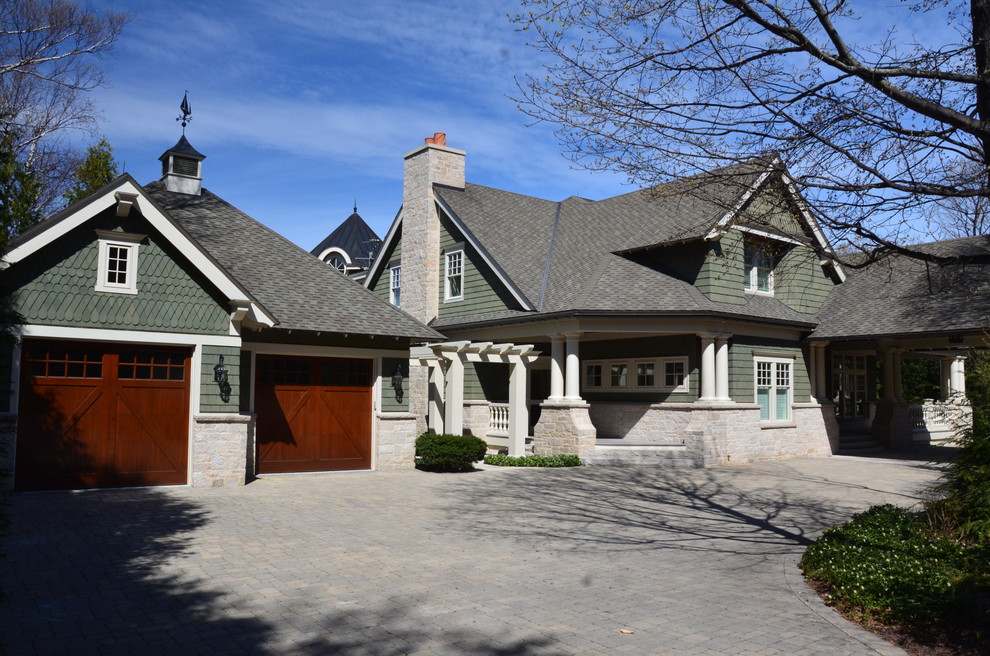 Photo of a large arts and crafts two-storey green house exterior in Other with wood siding, a gable roof and a tile roof.