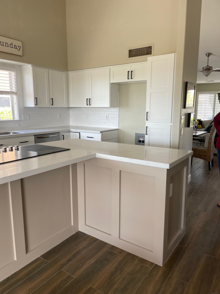 This is an example of a l-shaped kitchen in Phoenix with shaker cabinets, white cabinets, stainless steel appliances and an island.