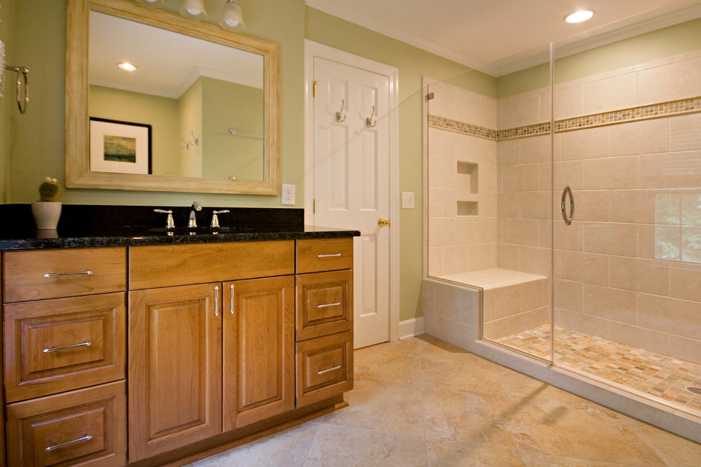 Photo of a mid-sized transitional master bathroom in Raleigh with raised-panel cabinets, medium wood cabinets, an alcove shower, a two-piece toilet, beige tile, cement tile, green walls, cement tiles, an undermount sink, granite benchtops, multi-coloured floor, a hinged shower door and green benchtops.