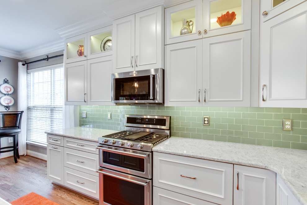 Kitchen - mid-sized transitional l-shaped medium tone wood floor kitchen idea in Baltimore with an undermount sink, recessed-panel cabinets, white cabinets, quartz countertops, green backsplash, subway tile backsplash, stainless steel appliances and an island