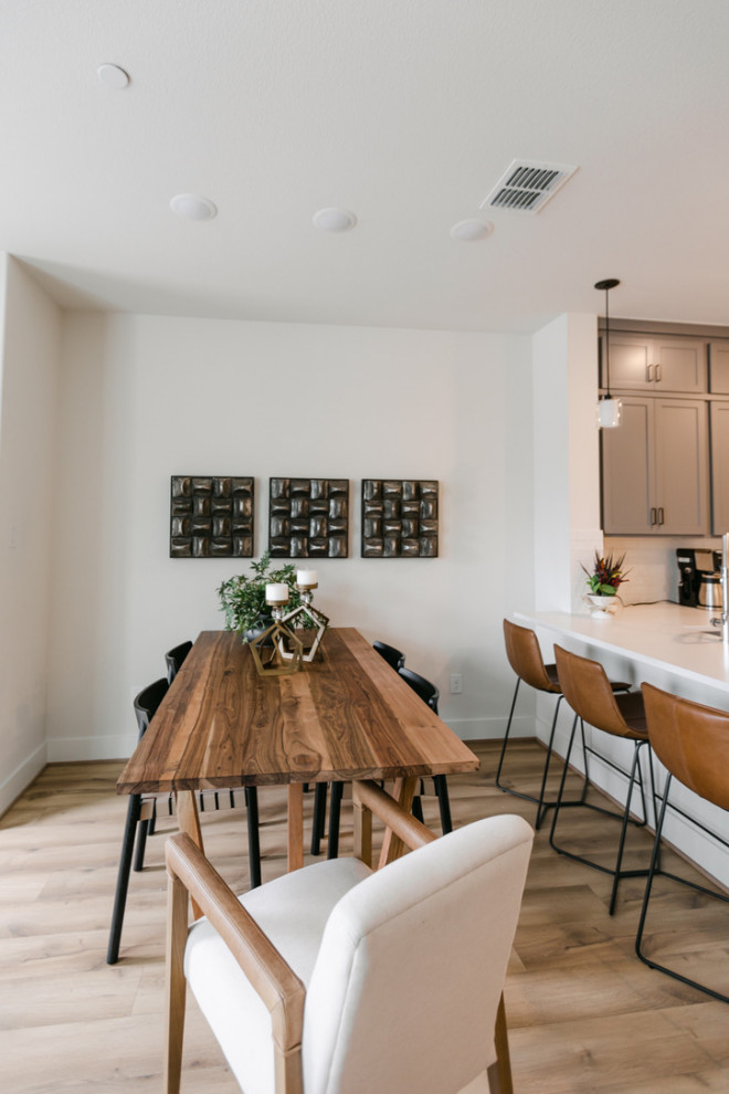 Cette image montre une petite salle à manger minimaliste avec un mur blanc, sol en stratifié, aucune cheminée et un sol marron.