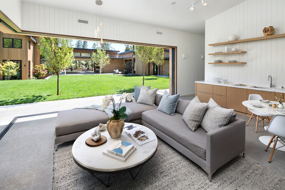 This is an example of a contemporary open concept living room in San Francisco with white walls and grey floor.