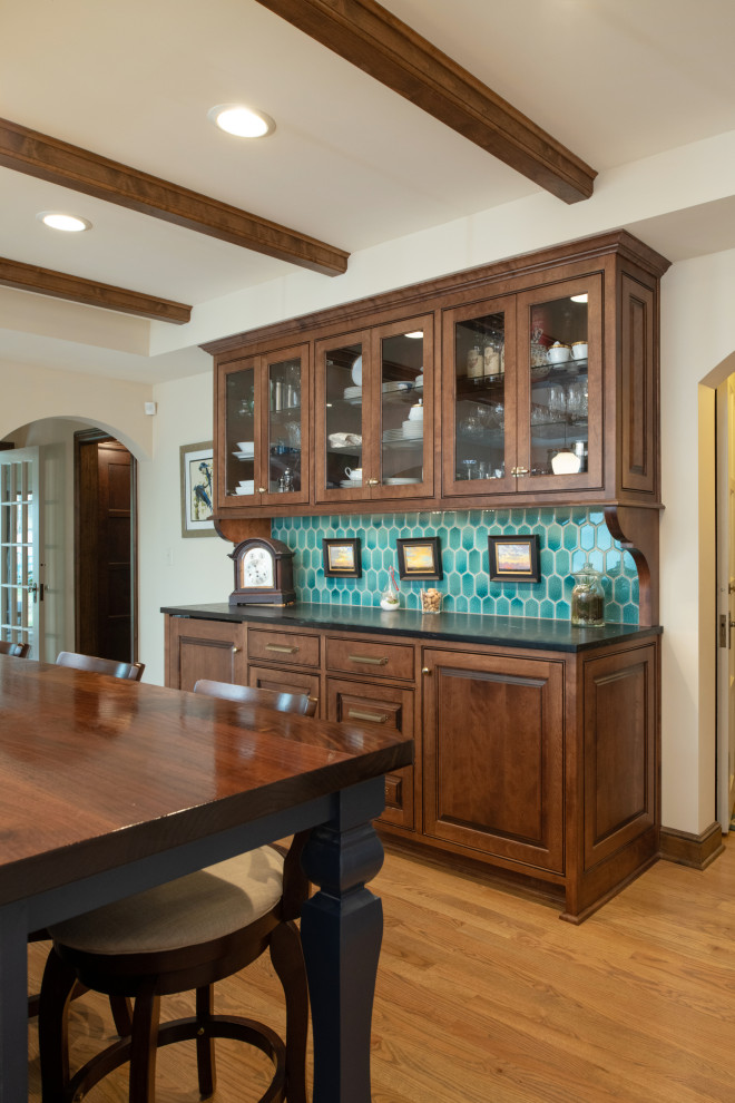 Large traditional kitchen in Kansas City with glass-front cabinets, dark wood cabinets, wood benchtops, blue splashback, ceramic splashback, panelled appliances, medium hardwood floors, with island, brown benchtop and exposed beam.