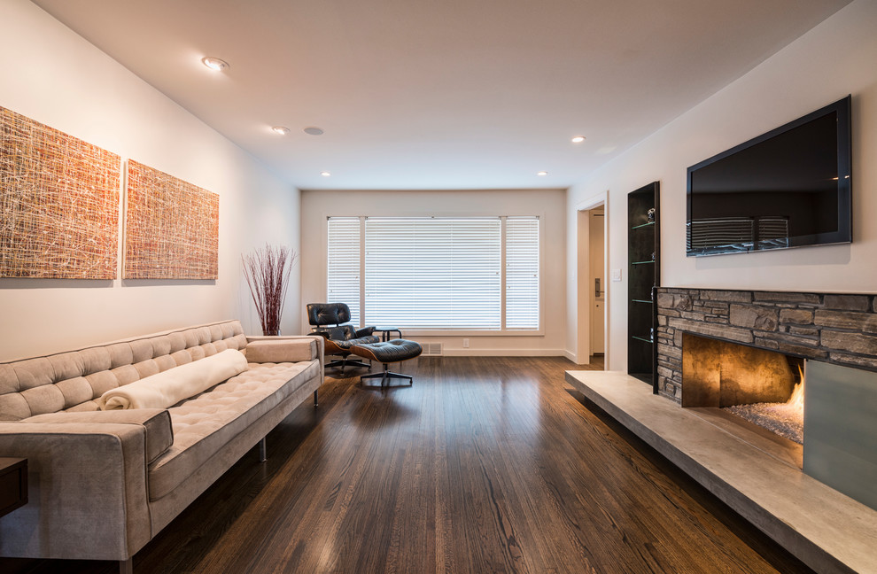 This is an example of a contemporary family room in Other with dark hardwood floors, a standard fireplace, a stone fireplace surround and a wall-mounted tv.