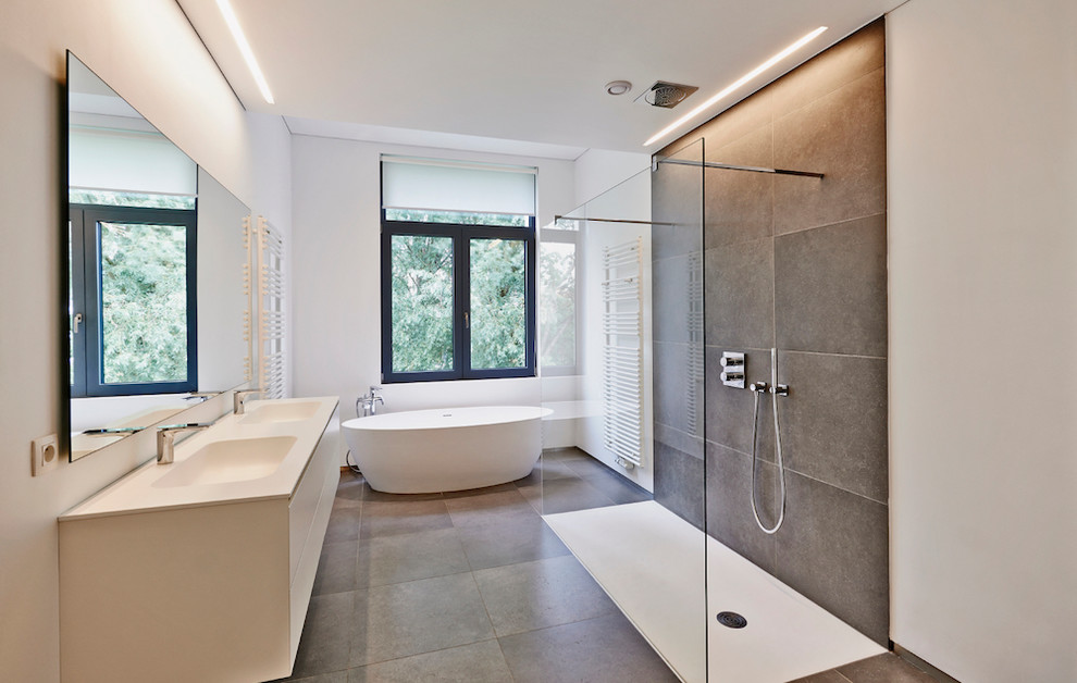 Design ideas for a large modern master bathroom in New York with flat-panel cabinets, beige cabinets, a freestanding tub, a corner shower, beige walls, cement tiles, a drop-in sink, engineered quartz benchtops and beige floor.