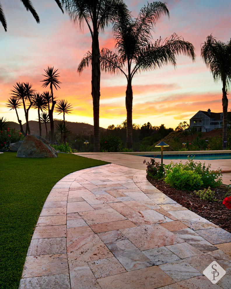 This is an example of an expansive mediterranean side yard patio in Orange County with natural stone pavers.