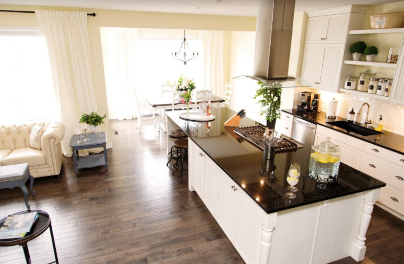 Open concept kitchen - mid-sized transitional single-wall laminate floor and brown floor open concept kitchen idea in Calgary with an undermount sink, louvered cabinets, white cabinets, solid surface countertops, white backsplash, subway tile backsplash, stainless steel appliances and an island
