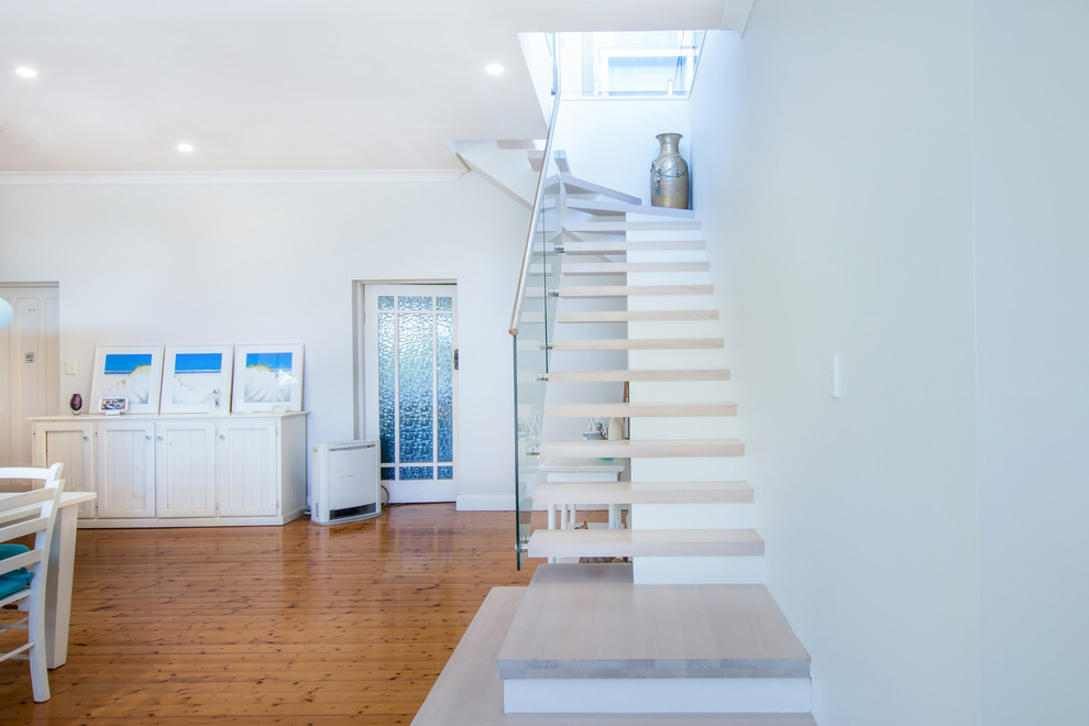 Photo of a mid-sized beach style wood curved staircase in Sydney with glass risers and mixed railing.