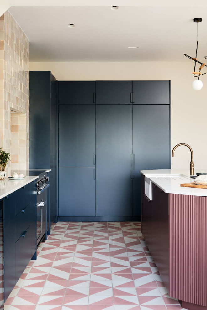 Large contemporary l-shaped kitchen in London with flat-panel cabinets, pink cabinets, cement flooring, an island, pink floors, grey worktops and a chimney breast.