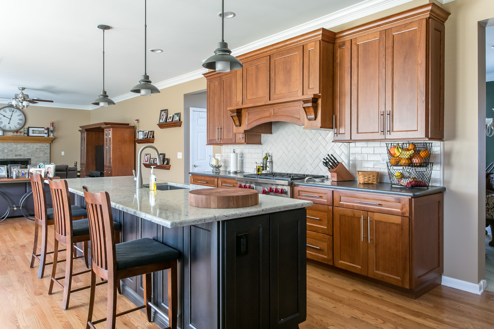 Mid-sized traditional u-shaped eat-in kitchen in Chicago with an undermount sink, shaker cabinets, medium wood cabinets, white splashback, subway tile splashback, stainless steel appliances, medium hardwood floors, with island, brown floor, quartz benchtops and multi-coloured benchtop.