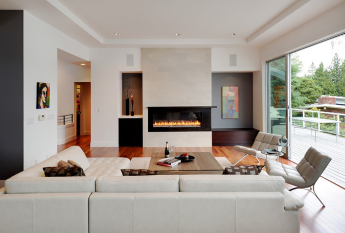 This is an example of a large contemporary formal open concept living room in Seattle with white walls, light hardwood floors, a ribbon fireplace, a metal fireplace surround and a freestanding tv.
