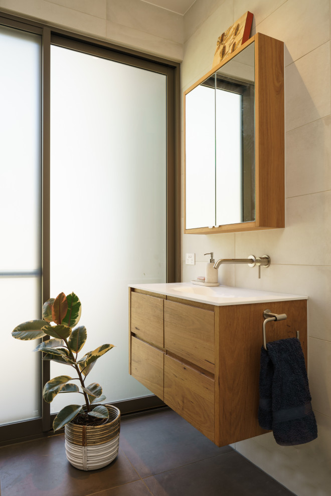 Design ideas for a contemporary cloakroom in Sunshine Coast with flat-panel cabinets, medium wood cabinets, beige tiles, an integrated sink, brown floors, white worktops and a floating vanity unit.