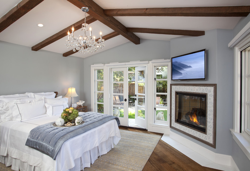 Mid-sized traditional master bedroom in San Diego with a corner fireplace, grey walls, dark hardwood floors, a tile fireplace surround and brown floor.