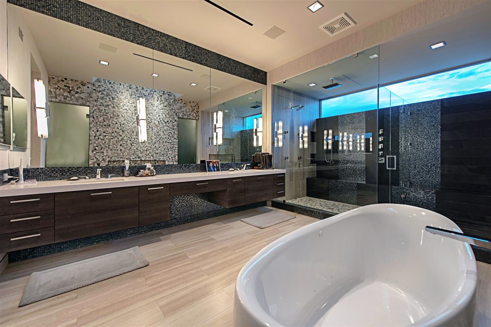 Inspiration for a large contemporary master bathroom in Las Vegas with flat-panel cabinets, dark wood cabinets, a freestanding tub, an alcove shower, multi-coloured tile, mosaic tile, multi-coloured walls, porcelain floors, an integrated sink, solid surface benchtops, beige floor and a hinged shower door.