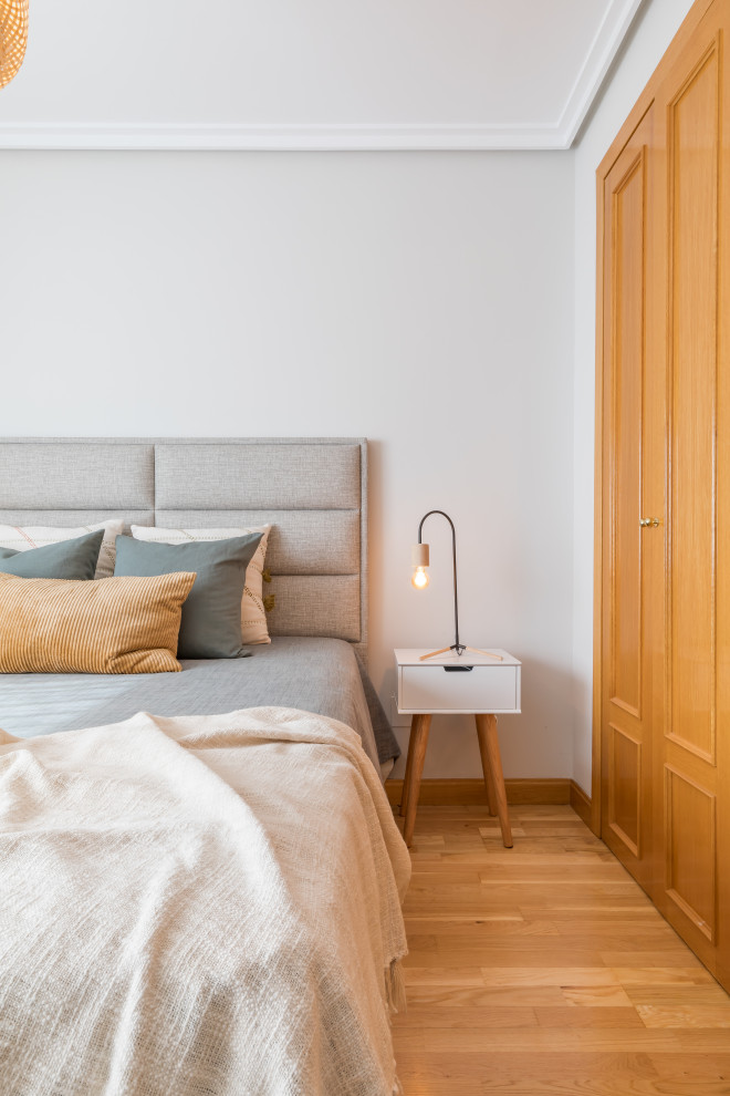 Medium sized scandinavian guest and grey and white bedroom in Madrid with grey walls, medium hardwood flooring and brown floors.