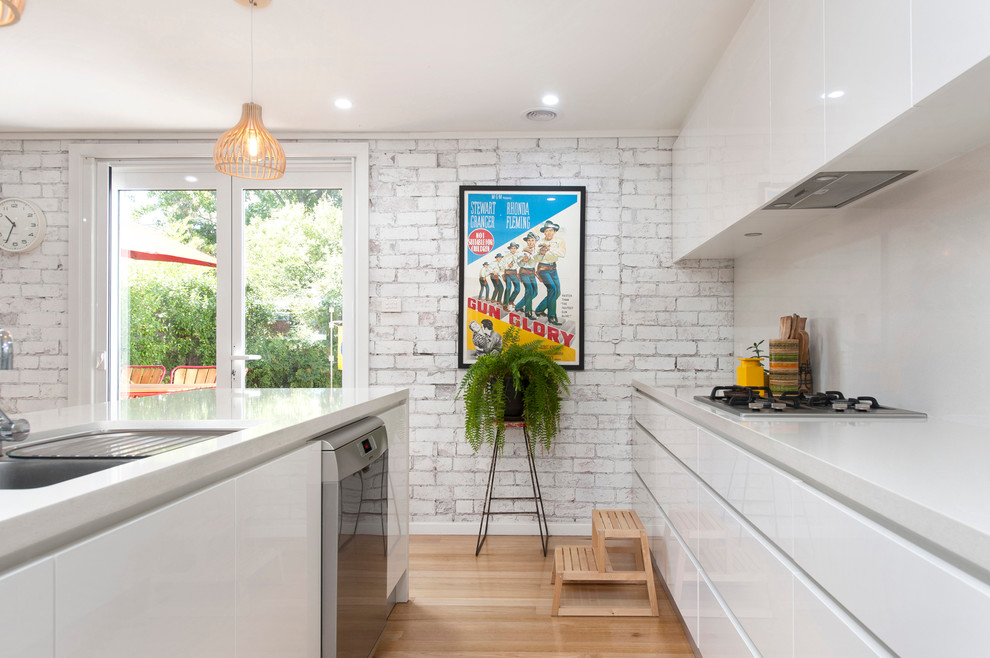 Photo of a small midcentury galley open plan kitchen in Canberra - Queanbeyan with an undermount sink, beaded inset cabinets, white cabinets, quartz benchtops, white splashback, stone slab splashback, stainless steel appliances, light hardwood floors and with island.