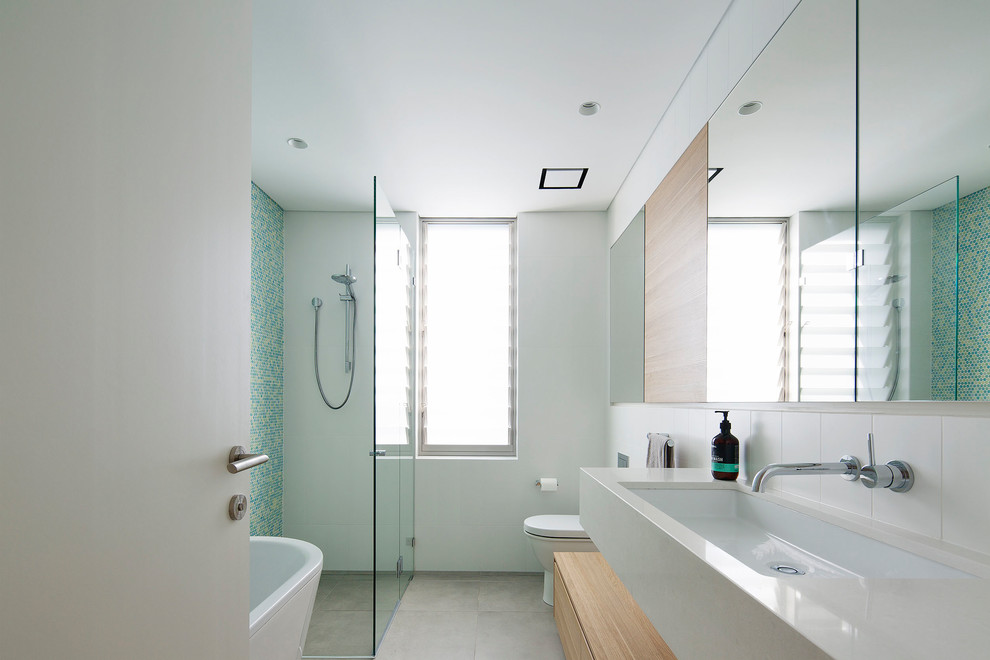 This is an example of a large modern kids bathroom in Sydney with a freestanding tub, a corner shower, green tile, mosaic tile, white walls, ceramic floors, an undermount sink, engineered quartz benchtops, grey floor and a hinged shower door.