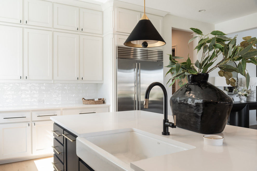 Inspiration for a large modern l-shaped open plan kitchen in Dallas with shaker cabinets, white cabinets, quartzite benchtops, white splashback, stainless steel appliances, light hardwood floors, with island, beige floor and white benchtop.