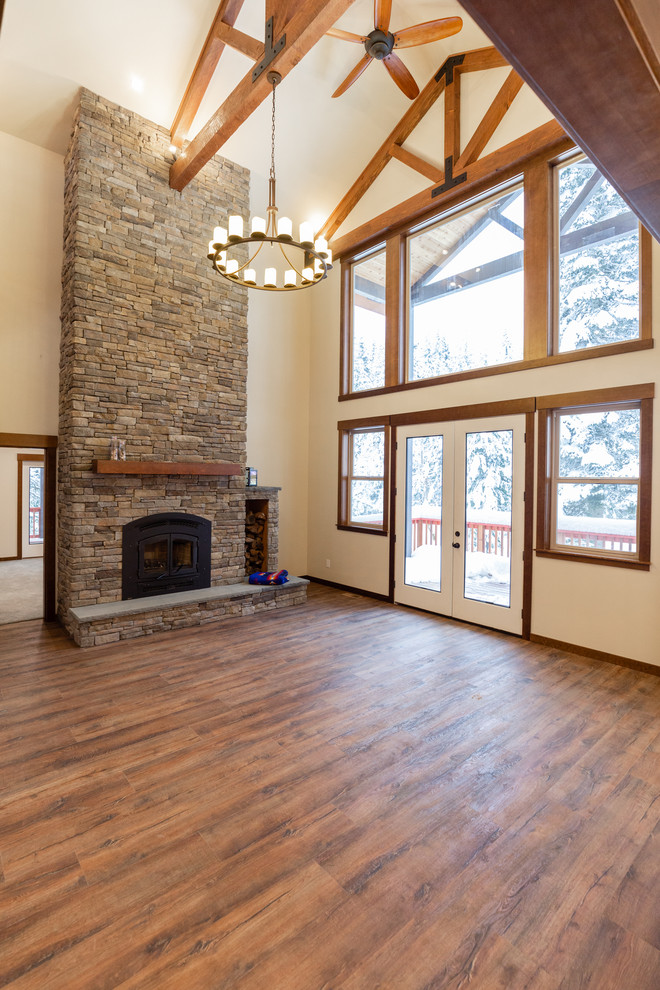 Photo of a large country loft-style living room in Portland with a wood stove and a stone fireplace surround.