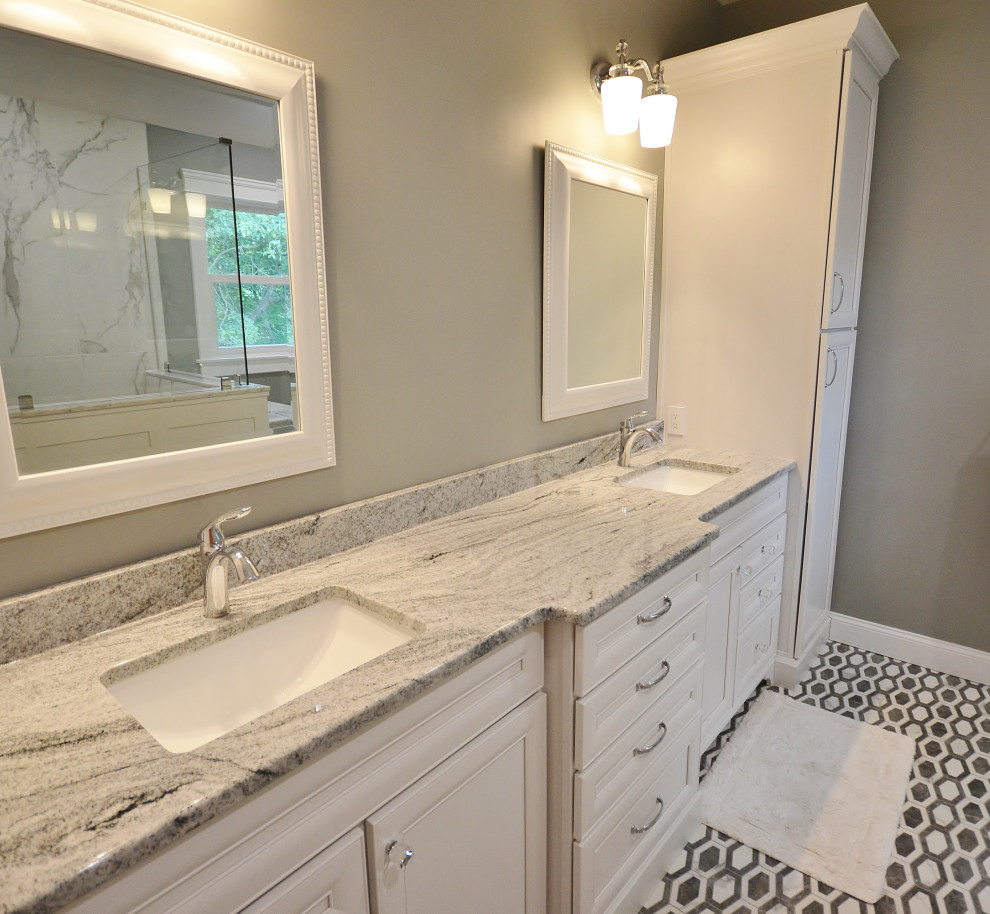 This is an example of a large transitional master bathroom in Philadelphia with raised-panel cabinets, white cabinets, a corner shower, a one-piece toilet, multi-coloured tile, marble, grey walls, mosaic tile floors, an undermount sink, granite benchtops, multi-coloured floor, a hinged shower door, multi-coloured benchtops, a shower seat, a double vanity and a built-in vanity.