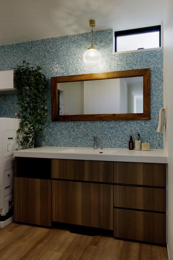 Foto på ett funkis vit toalett, med vita skåp, flerfärgad kakel, mosaik, mellanmörkt trägolv och beiget golv