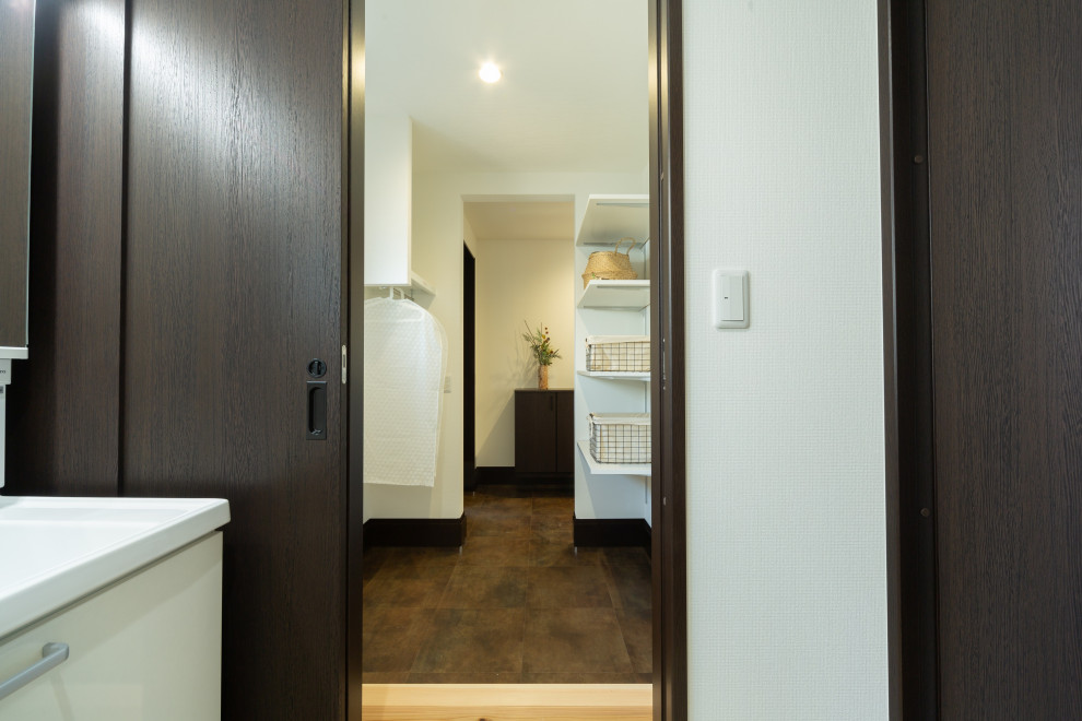 Photo of an asian entry hall in Kobe with white walls, terra-cotta floors, a single front door, a brown front door, black floor, wallpaper and wallpaper.