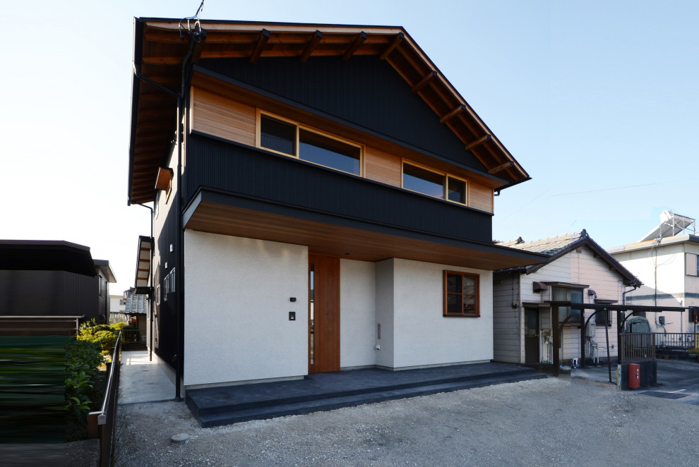 Réalisation d'une façade de maison métallique et noire asiatique de taille moyenne et à un étage avec un toit à deux pans, un toit en métal et un toit noir.