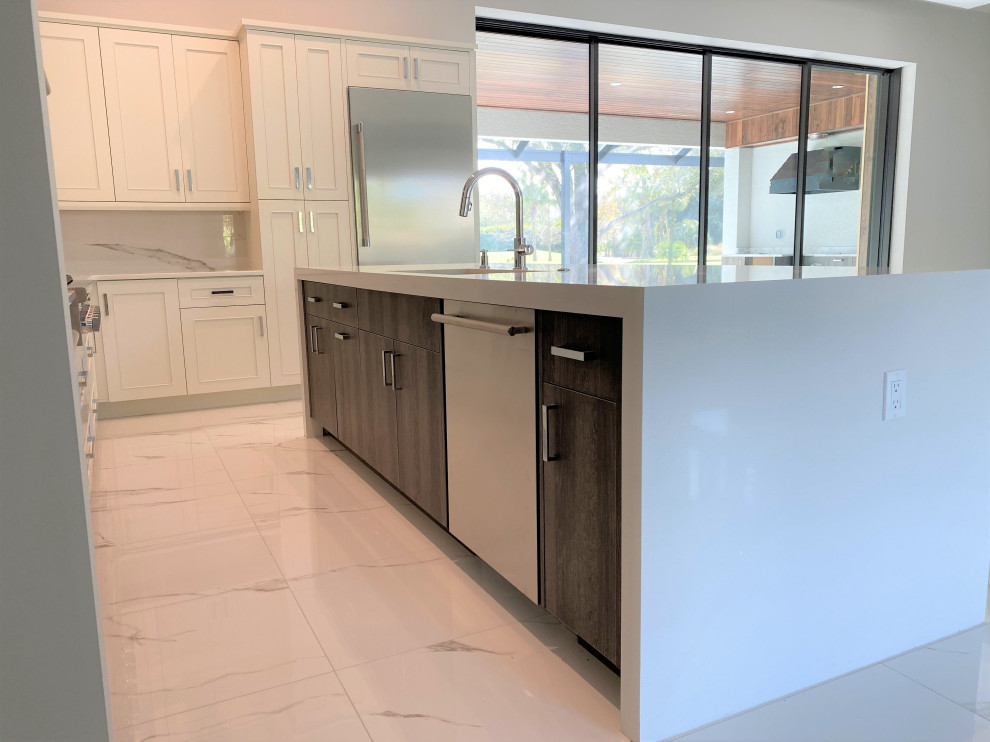 Inspiration for a mid-sized transitional l-shaped porcelain tile and white floor open concept kitchen remodel in Miami with an undermount sink, recessed-panel cabinets, beige cabinets, quartz countertops, white backsplash, porcelain backsplash, stainless steel appliances, an island and white countertops