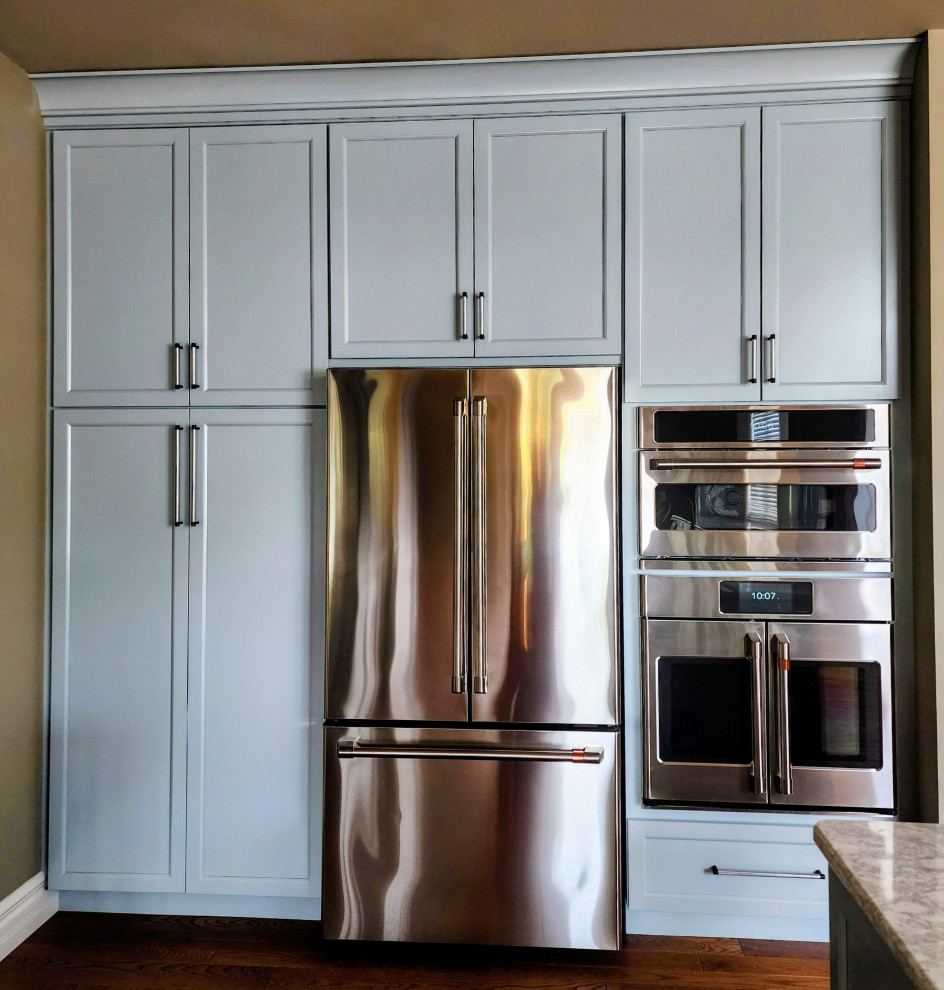 Mid-sized transitional medium tone wood floor and brown floor open concept kitchen photo with an undermount sink, shaker cabinets, quartz countertops, white backsplash, quartz backsplash, stainless steel appliances, an island and white countertops