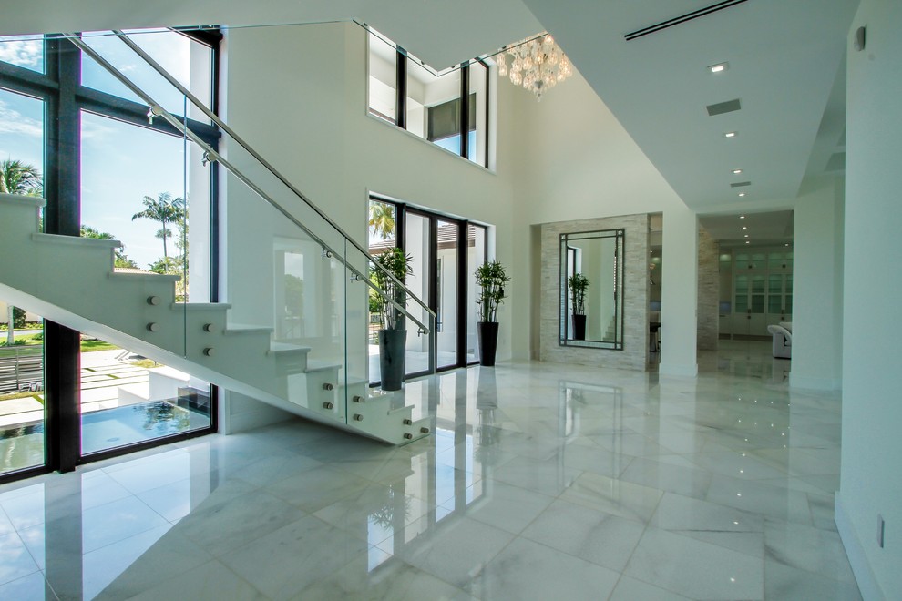 Photo of a large modern foyer in Miami with white walls, marble floors, a double front door, a glass front door and white floor.
