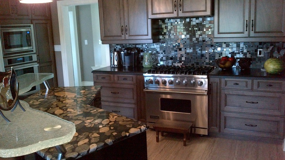 Inspiration for a large transitional u-shaped medium tone wood floor home design remodel in Toronto with recessed-panel cabinets, dark wood cabinets, onyx countertops, metallic backsplash, metal backsplash, stainless steel appliances and an island