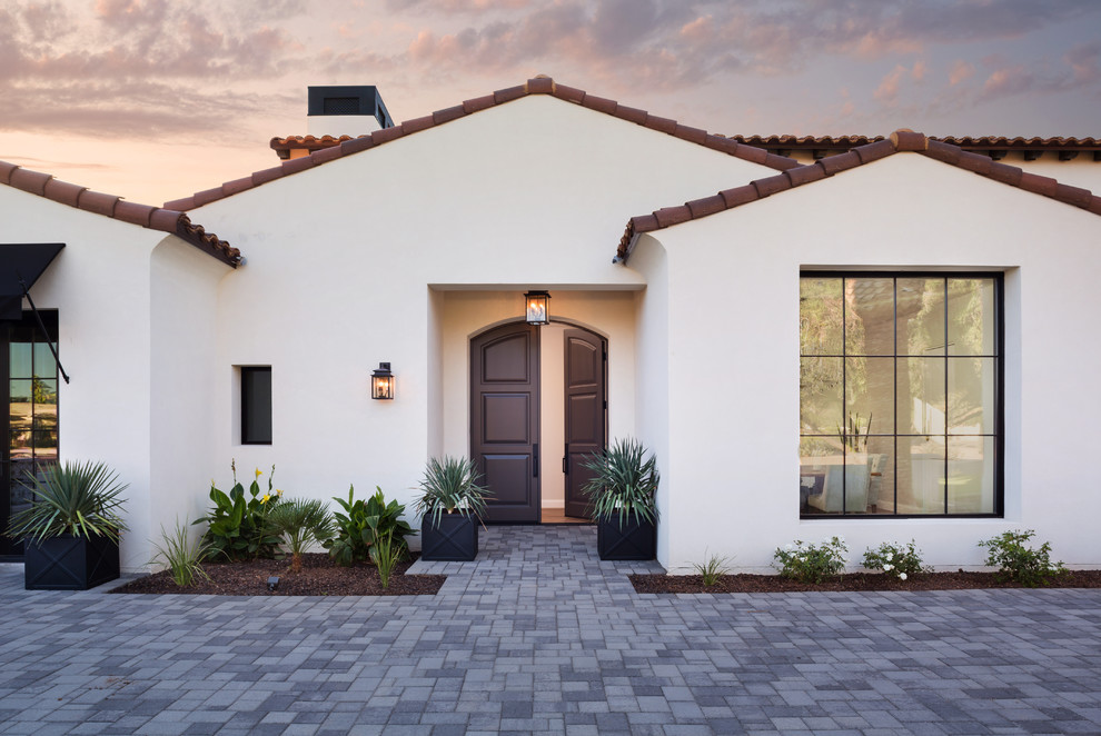 This is an example of a mediterranean entryway in Phoenix with white walls, a double front door and a dark wood front door.