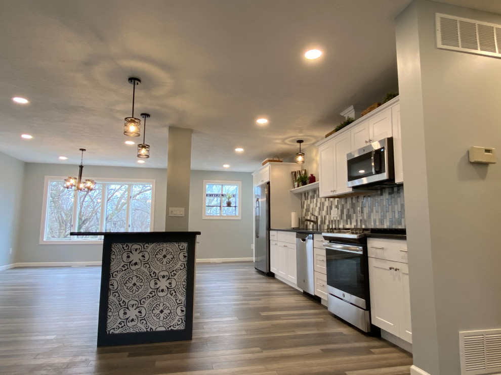 Inspiration for a large transitional l-shaped vinyl floor and gray floor open concept kitchen remodel in Cincinnati with an undermount sink, raised-panel cabinets, white cabinets, granite countertops, multicolored backsplash, ceramic backsplash, stainless steel appliances, an island and black countertops